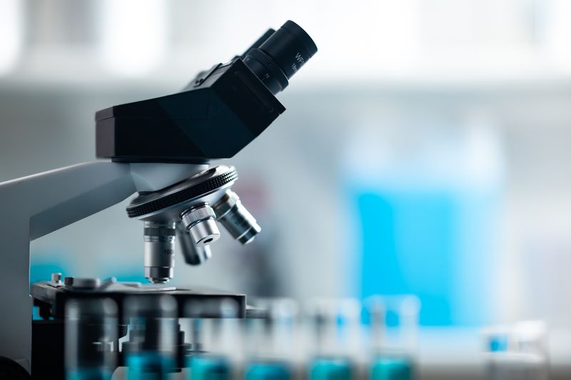 A laboratory microscope beside a rack of sample tubes.