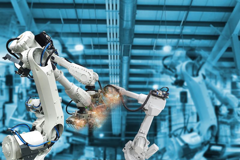 Two industrial robot arms working together in a factory.