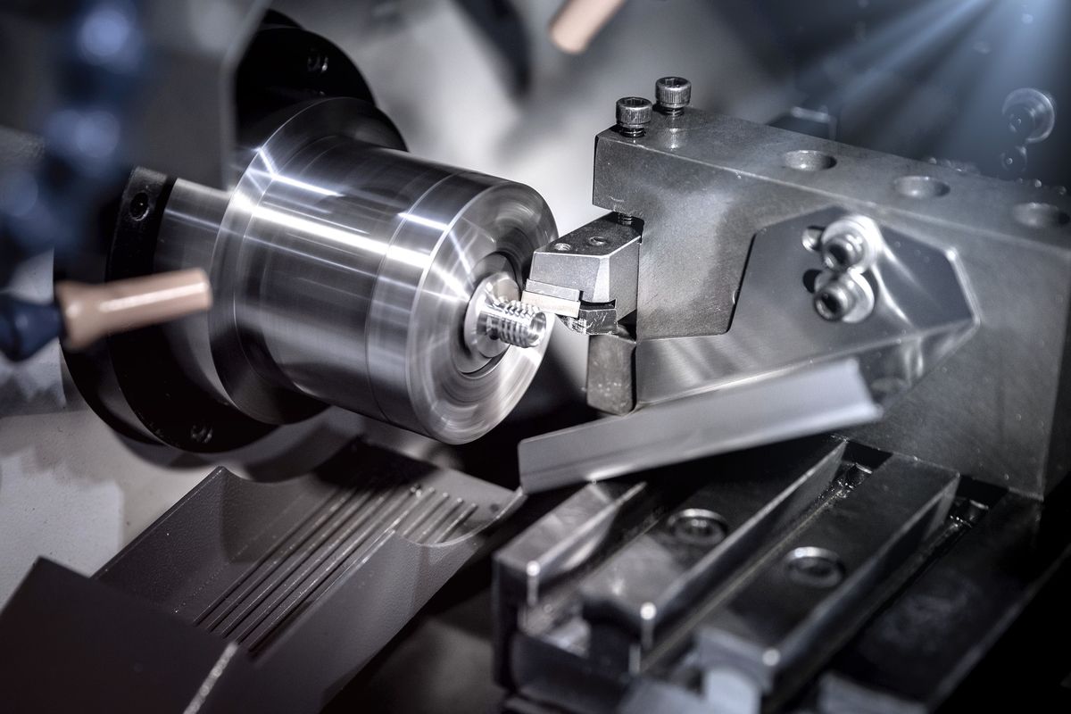 A cutting tool turning a threaded part on a CNC lathe.